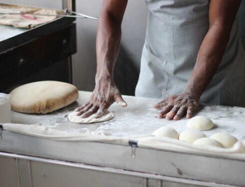 a man sculpts dough in an apron