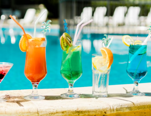 colorful cocktails with straws in front of pool