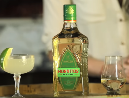 A tequila hornito on a table, accompanied by a glass containing lemon slices