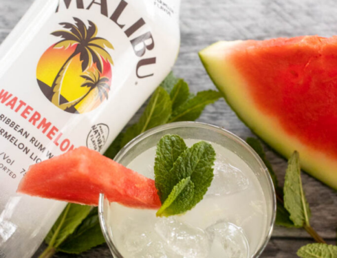 A bottle of malibu and a cocktail lie side by side on the table